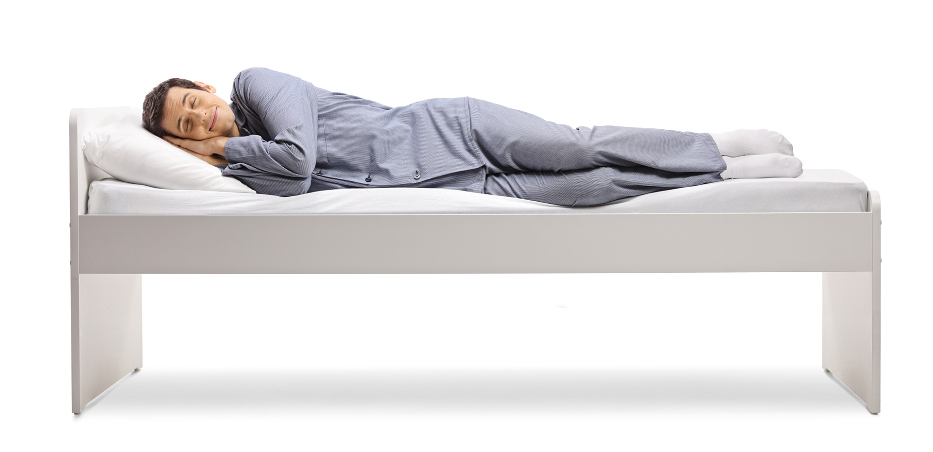 Un homme est allongé sur le côté dans un lit et sourit. 