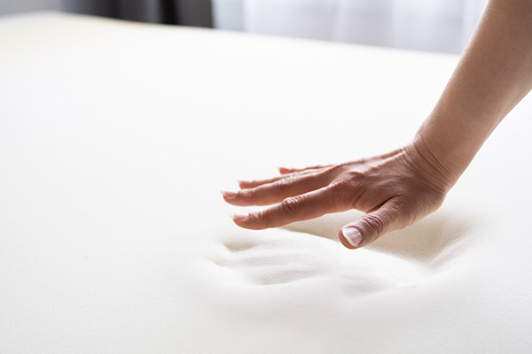 Une main que se soulève d'un matelas et on voit la forme de la main laissée sur un matelas en mémoire de forme.