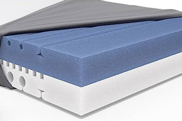 La housse du matelas est ouverte à moitié laissant percevoir l'âme du matelas en mousse bicolore : bleu et blanc. 